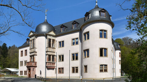 Das Wächtersbacher Schloss von außen: Ein weies Schlösschen mit grauem Dach und runden Türmen